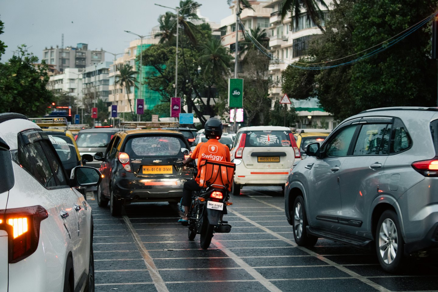 Delivery rider on a motorcycle navigating through dense city traffic.