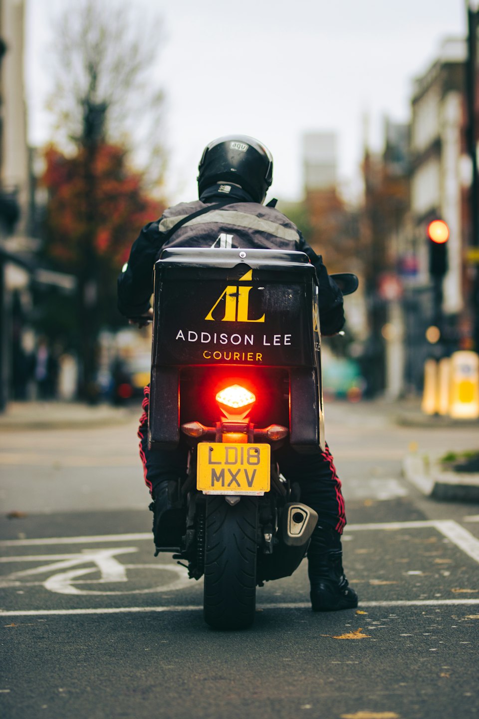 Delivery rider on motorcycle at city stop light.