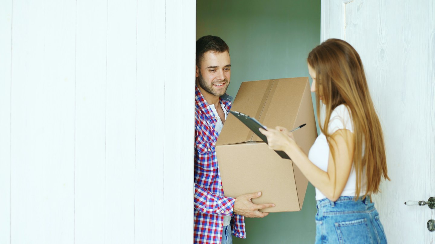 Man delivering package to woman signing for it.